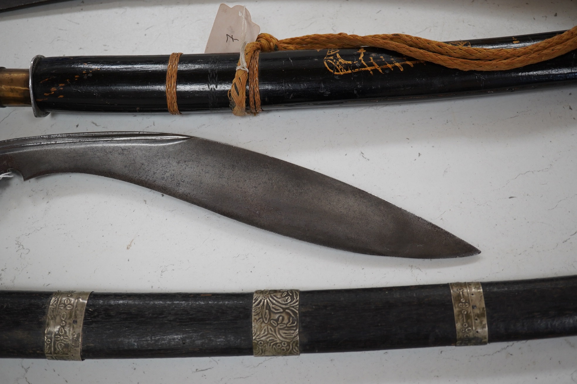 Four bladed weapons; an Indian sword Tulwar, blade 68.5cm. Condition - poor, heavily pitted., A Nepalese Kukri. Condition - fair., A Thai sword Dha, with a lacquered hilt and wooden scabbard, blade 56cm. Condition - fair
